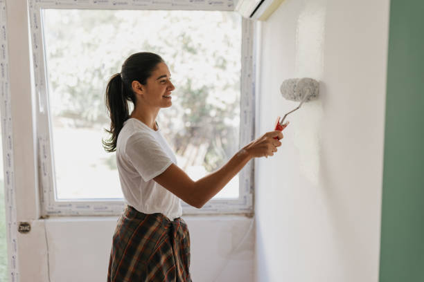 istock Woman Painting Wall with Roller in Natural Light 2199343745