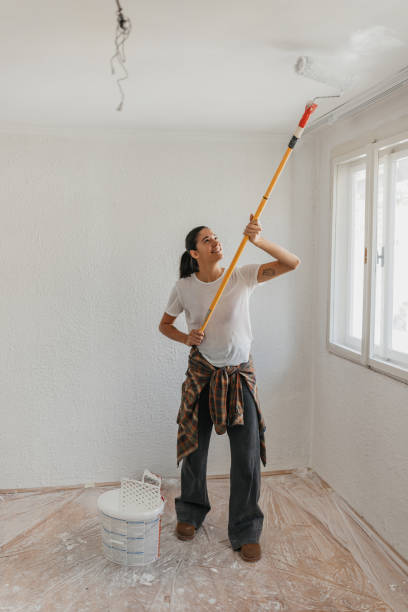 istock Woman Painting Ceiling with a Roller Brush 2199343802