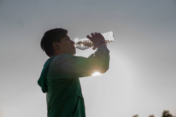 istock Asian male runner drinks water and rests after running in a park. 2199345974