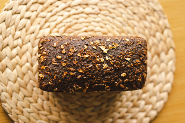 Sourdough bread, freshly baked and still warm, are stacked on a wooden surface. The bread are covered in seeds sesame and sunflower, adding a rustic and flavorful touch.