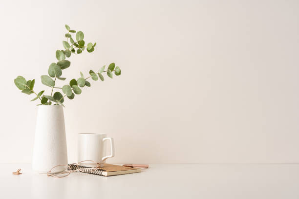 istock A minimal desk setup featuring a white vase with eucalyptus, a notebook, glasses, and a mug. Perfect for concepts of simplicity, organization, and a serene workspace environment 2199347788