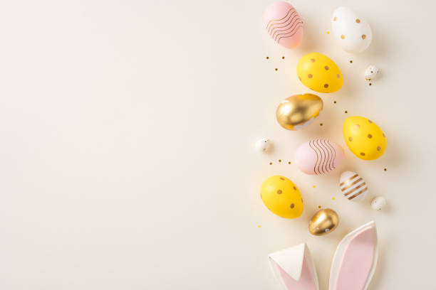 istock Decorative Easter eggs in gold, yellow, and pink hues with bunny ears, arranged elegantly 2199347798