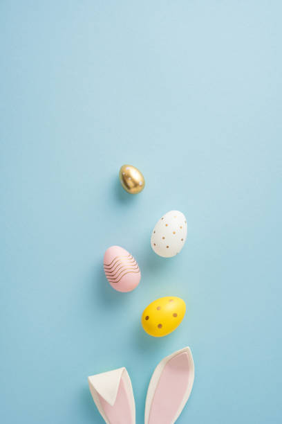 istock A vertical top view of colorful Easter eggs and bunny ears arranged on a soft blue background showcasing festive Easter themes 2199347803