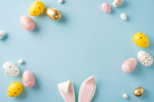 istock Colorful pastel Easter eggs and paper bunny ears arranged artistically on a blue surface 2199347804