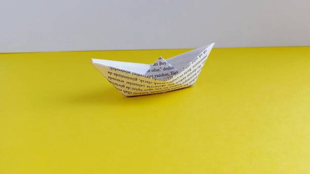 istock paper boat origami on yellow background 2199350657