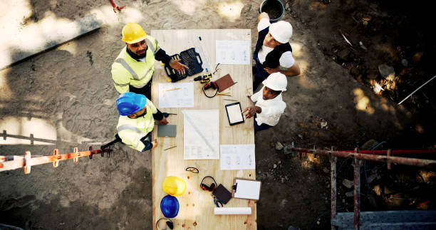 istock Blueprint, construction and people at table with layout, discussion or collaboration from above. Architect, building project manager and contractor on site with floor plan, team and safety inspection 2199351013