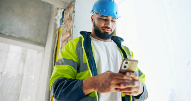 istock Man, phone and construction worker with texting, reading and contact with info for building development. Engineer, smartphone and chat with low angle, notification and click on mobile app at property 2199351106