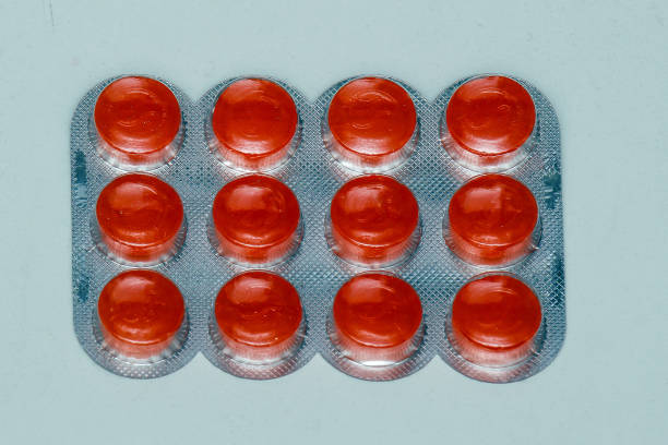 Orange throat lozenges in silver foil isolated on white