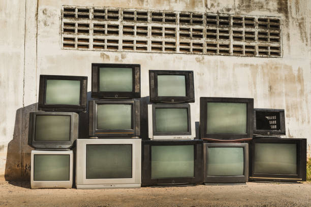 istock Retro old TVs pile on floor in front of old wall. Stack television sets with vintage filter effect. 2199353612