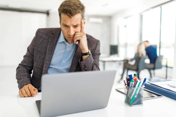 istock Pensive businessman working on laptop at corporate office. 2199354708