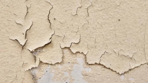 istock The yellow wall, whose paint has peeled off because it is old and exposed to rain and heat, needs to be repaired and repainted. Abstract background template. 2199355455