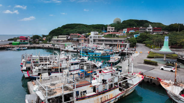 istock Fishing boats docked in a Taiwan harbor on a clear day, surrounded by greenery 2199356219