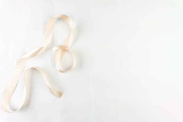 istock An ivory satin ribbon, elegantly curled against a stark white background, exudes sophistication and minimalist charm. 2199356903