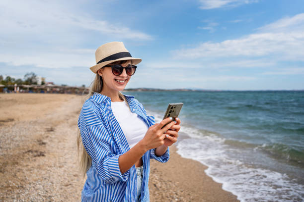 istock Young woman using smartphone on the beach 2199357837