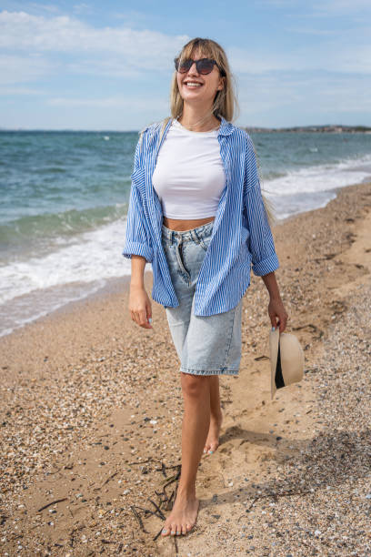istock Woman walking on the beach 2199358390