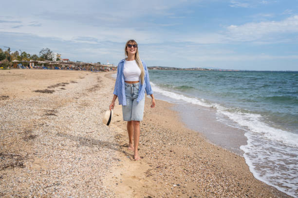 istock Woman walking on the beach 2199358440