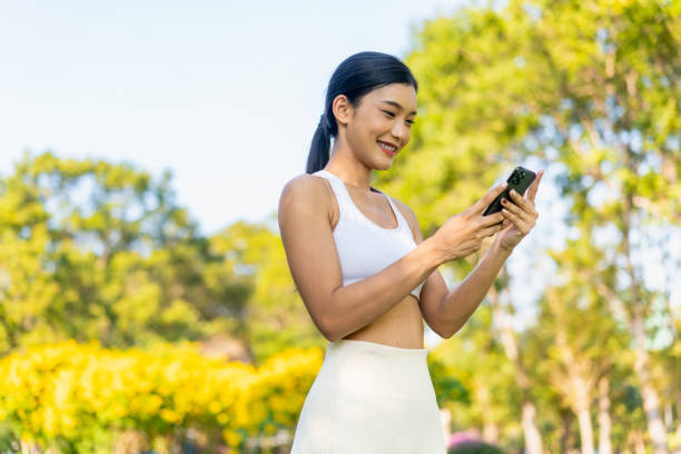 istock Young Asian Woman Using Phone in Green Park During Workout 2199358596