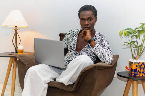 istock Happy non-binary African person sitting in an armchair using laptop working from home. African person. Casual work. Brazil, Rio de Janeiro. Freelancer 2199360035