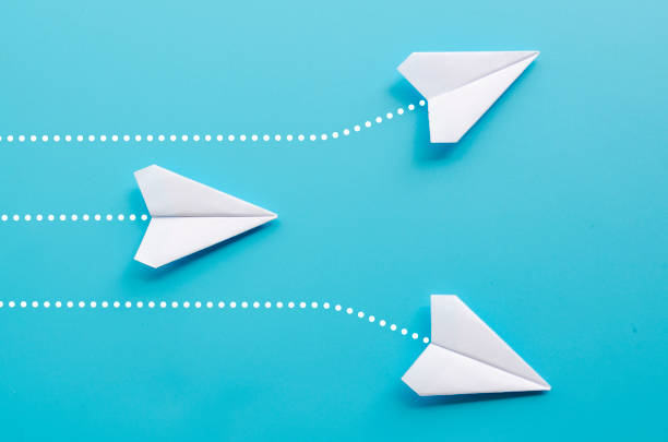 istock Top view of 3 white paper airplane heading to different direction on blue background 2199360999