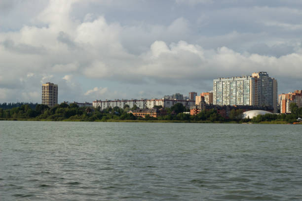 Grassland and urban architecture by the cloudy lake