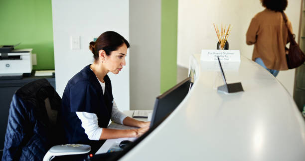istock Clinic, receptionist and woman on computer for medical service, appointment and administration. Healthcare, hospital and dental assistant at front desk for planning, online schedule and information 2199377502