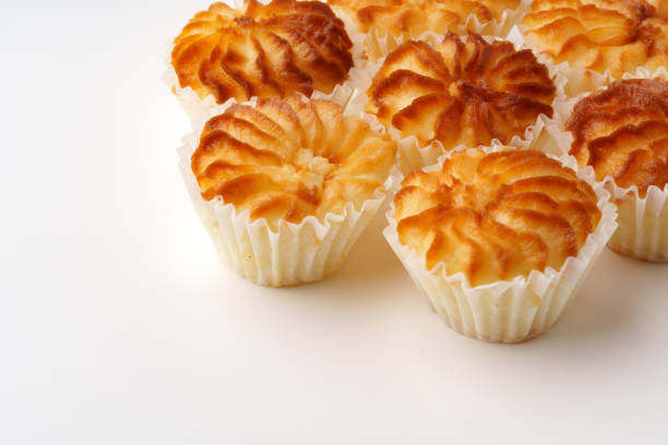 Freshly baked pastries with a golden-brown crust are arranged in a circular pattern on a clean white surface. The warm kitchen ambiance enhances their inviting appearance.