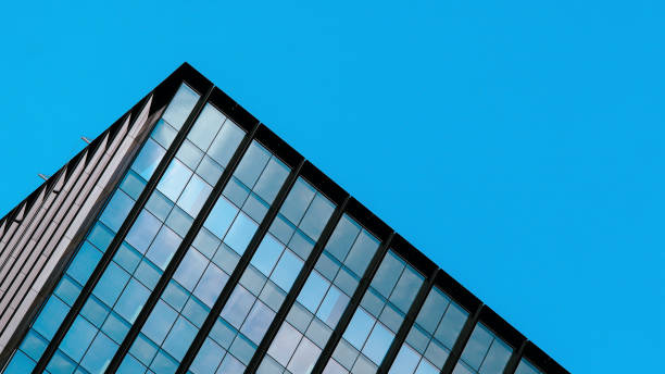 istock Modern office building with reflective glass panels under a clear blue sky, emphasizing contemporary architecture and geometric design. Perfect for urban and corporate-themed visuals 2199378750