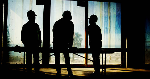 Silhouette, teamwork and architect with blueprint on site for building inspection, property development and planning. Construction worker, people and floor design for remodeling or safety compliance