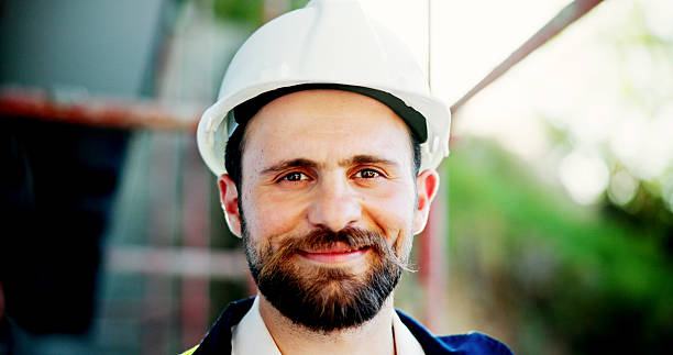 istock Smile, man and face of construction worker on site for city planning with building development. Happy, confident and portrait of male civil engineer with industrial architecture in town. 2199378770