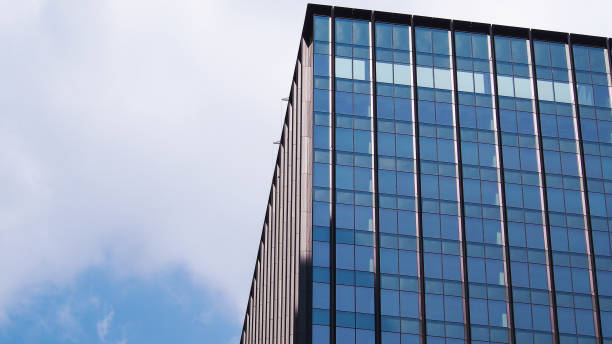 Contemporary high-rise building with sleek glass panels reflecting the sky, emphasizing clean lines and modern urban design. Perfect for illustrating themes of architecture and city development