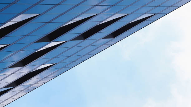 istock Modern building facade with geometric design and reflective glass panels, showcasing a blend of sharp angles and minimalistic aesthetics. Ideal for themes of contemporary architecture and urban innovation 2199378882
