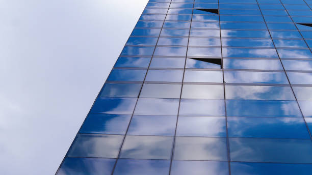 Fractured Reflections: Open Windows Disrupting the Sky's Seamless Canvas on a Glass Facade