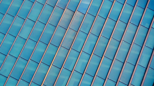 istock A grid of reflective glass panels creates a dynamic pattern, blending hues of blue and gold from light and shadow. 2199380861