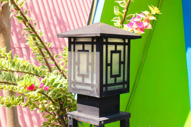 A black metal lantern stands against a vibrant pink and green wall, adorned with pink bougainvillea.
