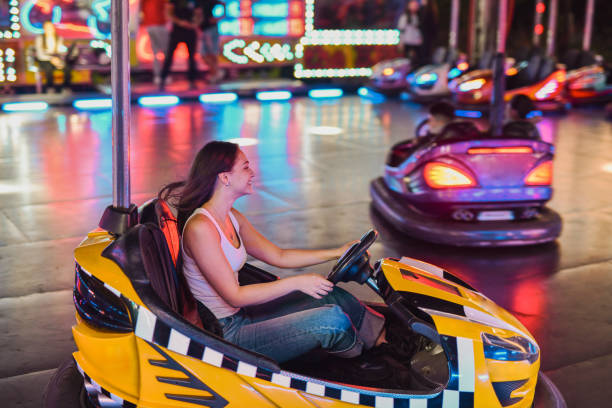 istock Joyful Female Driving Bumper Car At Amusement Park Enjoying Fun Night 2199382671