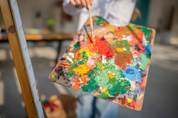 istock Young woman immersed in creative expression at home with vibrant paints and a canvas in a cozy living space 2199383709