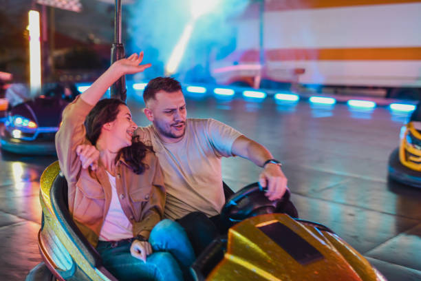 istock Boyfriend Driving Bumper Car With One Hand While Embracing Girlfriend Who's Cheering on Him 2199385141