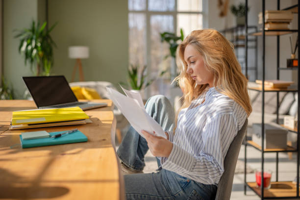 istock Young woman enjoying a quiet afternoon at home while reviewing important documents in a modern living space 2199385905