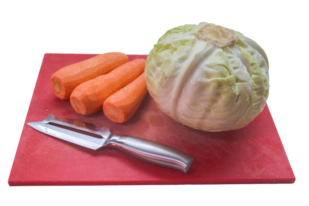 Cabbage carrots and a tumbling knife on a red cutting board isolated on a white background. Veganism and raw food diet concept.