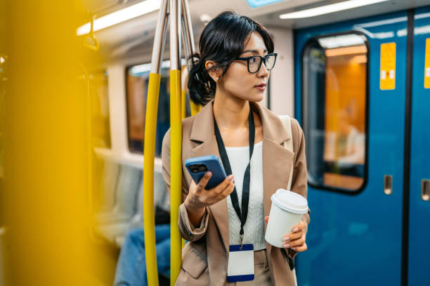 istock Young Asian Businesswoman Using Phone And Drinking Coffee To Go While Riding In A Subway Train In Sydney In Australia 2199390530