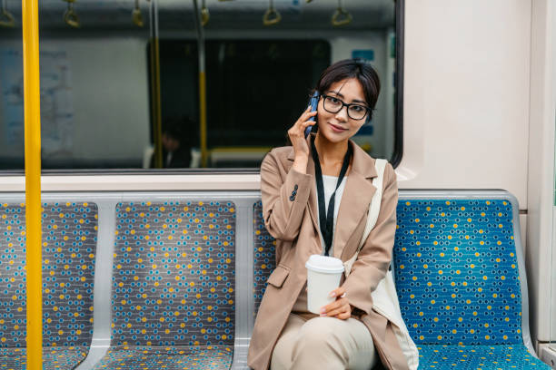 istock Young Asian Businesswoman Using Phone And Drinking Coffee To Go While Riding In A Subway Train In Sydney In Australia 2199390826