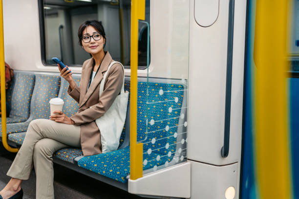 istock Young Asian Businesswoman Using Phone And Drinking Coffee To Go While Riding In A Subway Train In Sydney In Australia 2199391913