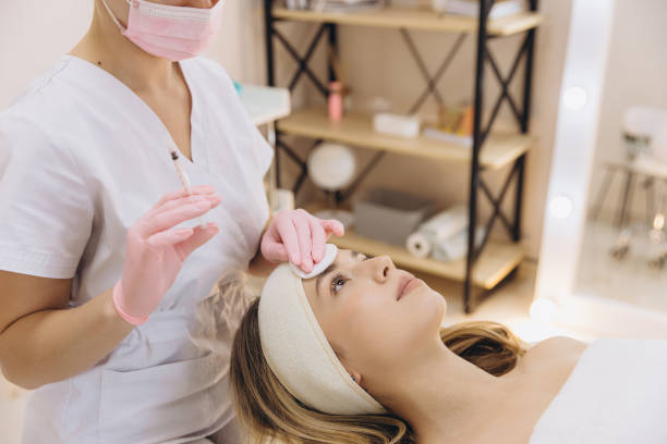 istock Professional cosmetologist cleaning client's forehead, preparing sterile botox procedure in modern beauty salon treatment room 2199393158