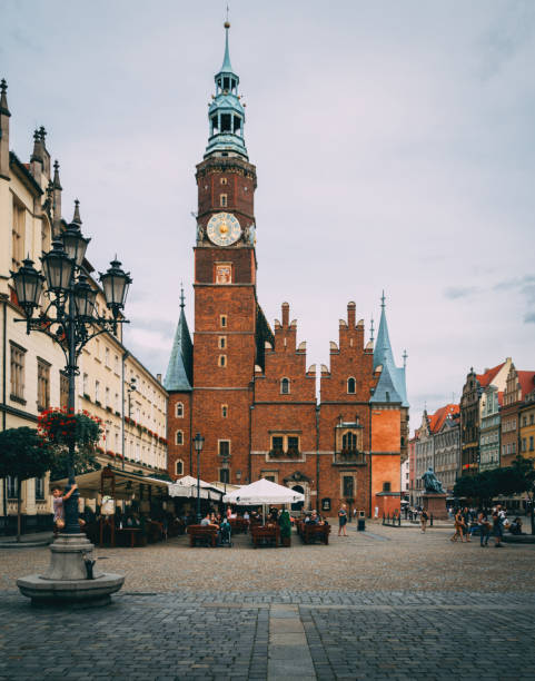 Bustling Market Square in Wroclaw, Poland, features the iconic town hall with a striking clock tower, surrounded by colorful buildings and lively outdoor cafes