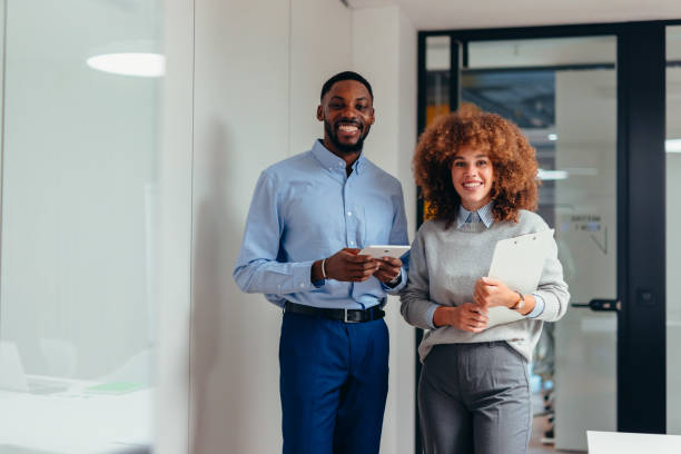 istock Smiling business partners holding digital tablet and documents in office corridor 2199394978