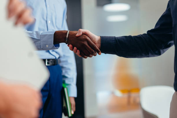 istock Businessmen shaking hands in modern office after successful meeting 2199395056