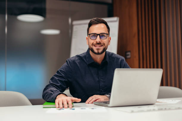 istock Businessman smiling and working with laptop in modern office 2199395083