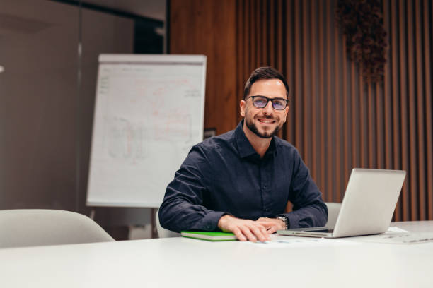 istock Businessman smiling and working with laptop in the office 2199395088