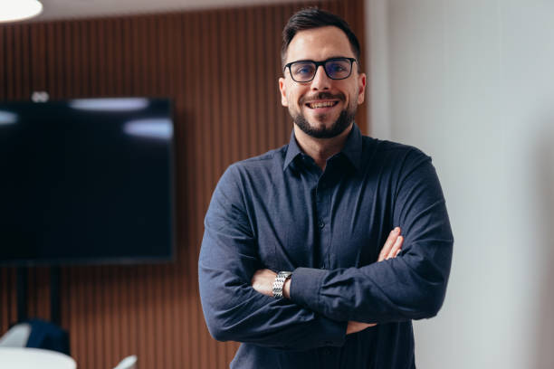 istock Businessman smiling with arms crossed in modern office 2199395232
