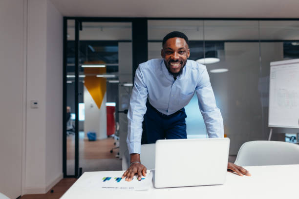 istock Smiling businessman leaning on meeting table with laptop and paperwork 2199395286
